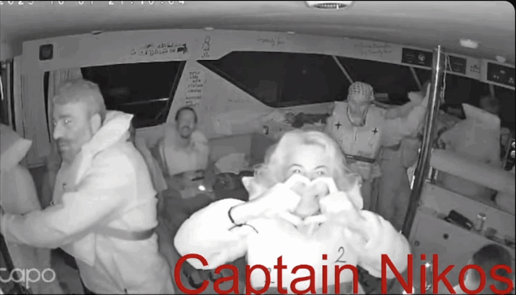 screenshot van de livestream van de Captain Nikos, een van de boten van de Global Sumud Flotilla. Een van de opvarenden maakt een hartje met diens handen richting de camera.